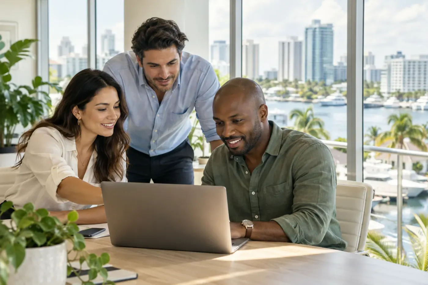 Team working at a laptop in a Fort Lauderdale office
